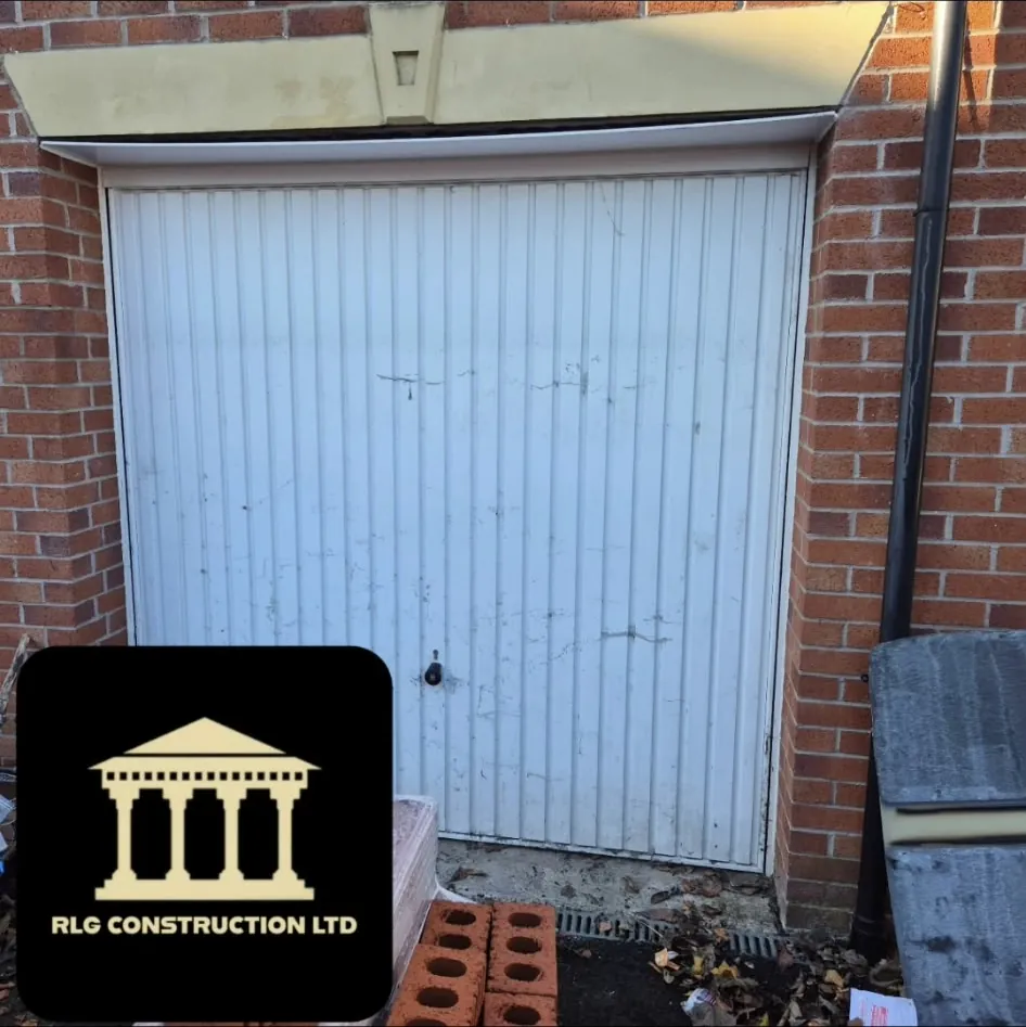 The old white garage door in a brick opening with a stone lintel above, before the conversion